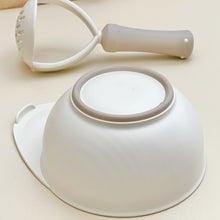 Load image into Gallery viewer, Non slip ring on the bottom of a masher bowl. Ring is in beige color. Hand masher is in neutral color.
