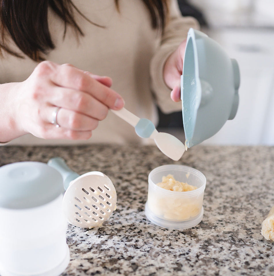 After mashing food with masher and bowl with handle, parent pours homemade baby food into littoes food pot baby food storage.