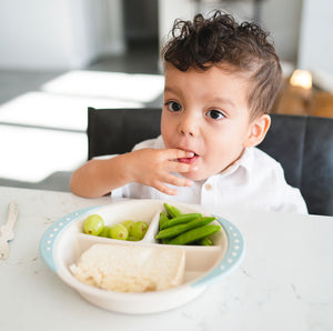 Boy eating food using littoes sectioned plate with easy grip side handles. Littoes dinner plate has three sections non slip base to keep the plate in place on table